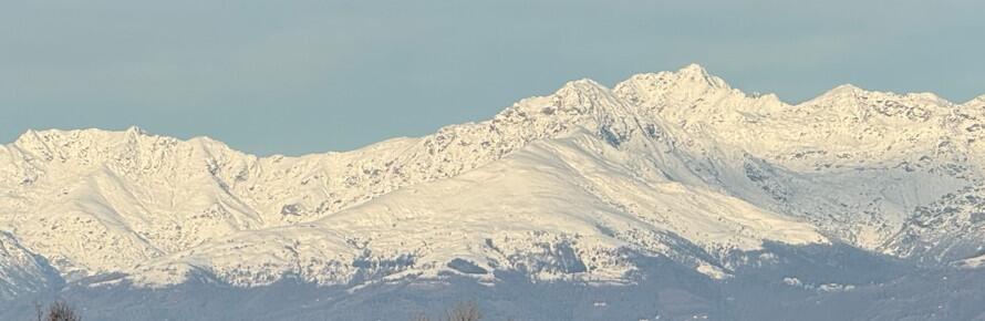 Snow-covered Alps rising above Biella, Italy under a clear winter sky