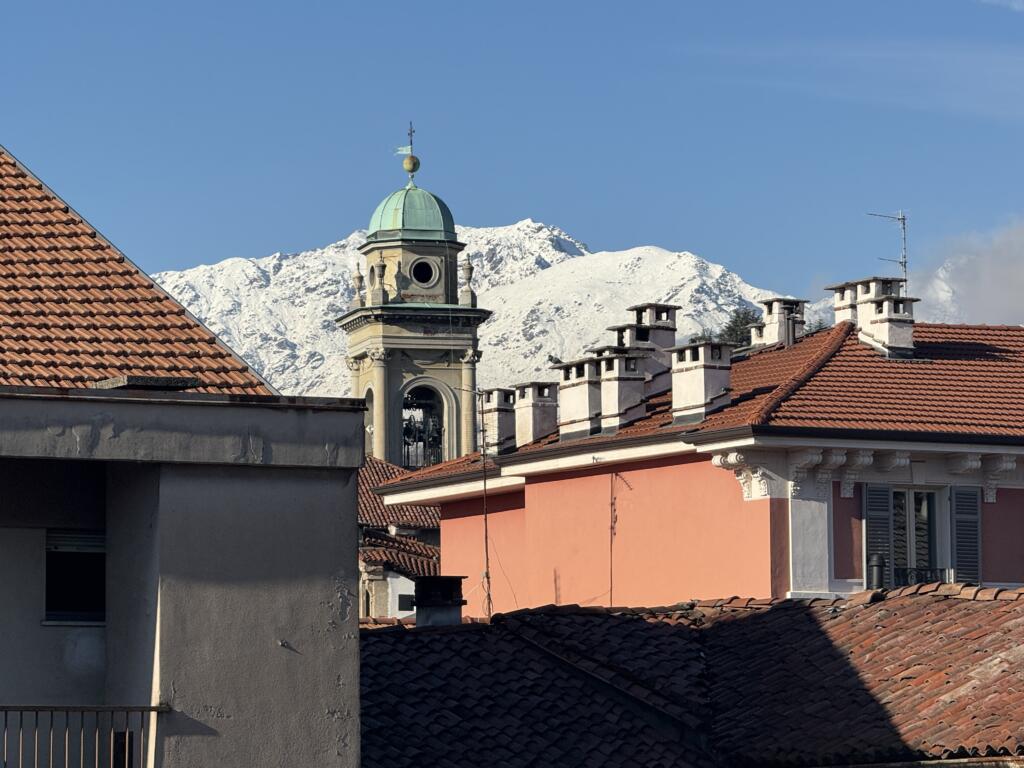 Snow-covered Alps rising above historic rooftops in Biella, Italy