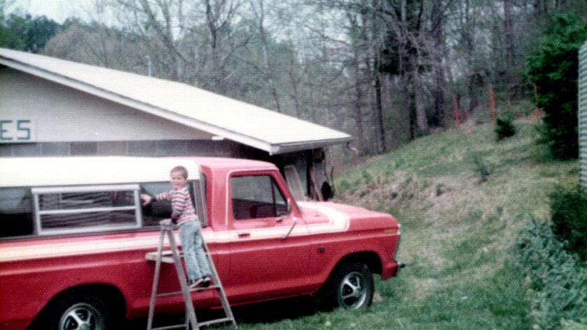 Young Ryan Gartrell washing his grandfather’s red pickup truck outside antique shop in rural Tennessee in the 1970s