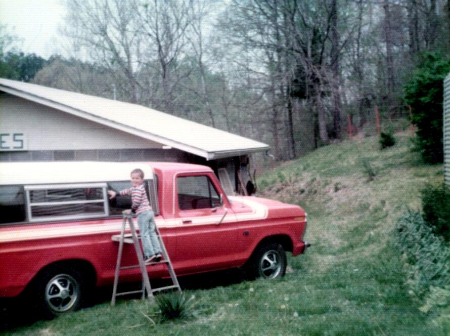 Young Ryan Gartrell washing his grandfather’s red pickup truck outside antique shop in rural Tennessee in the 1970s