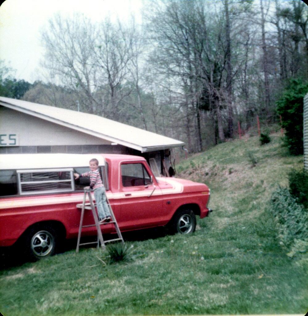 Young Ryan Gartrell washing his grandfather’s red pickup truck outside antique shop in rural Tennessee in the 1970s