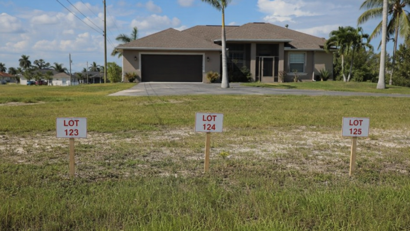 Cape Coral home spanning three lots with a property tax bill and future water and sewer expansion sign.